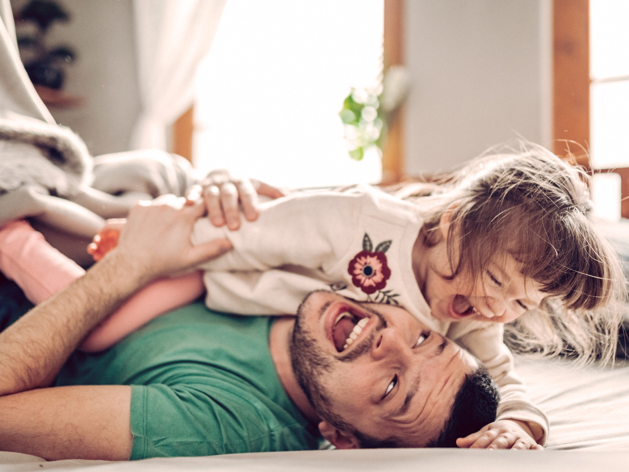 Foto zeigt einen Vater, der mit seiner Tochter tobt. Die Eltern des Kindes haben bei der Wahl der Erkältungssalbe auf ein mildes Produkt gesetzt.