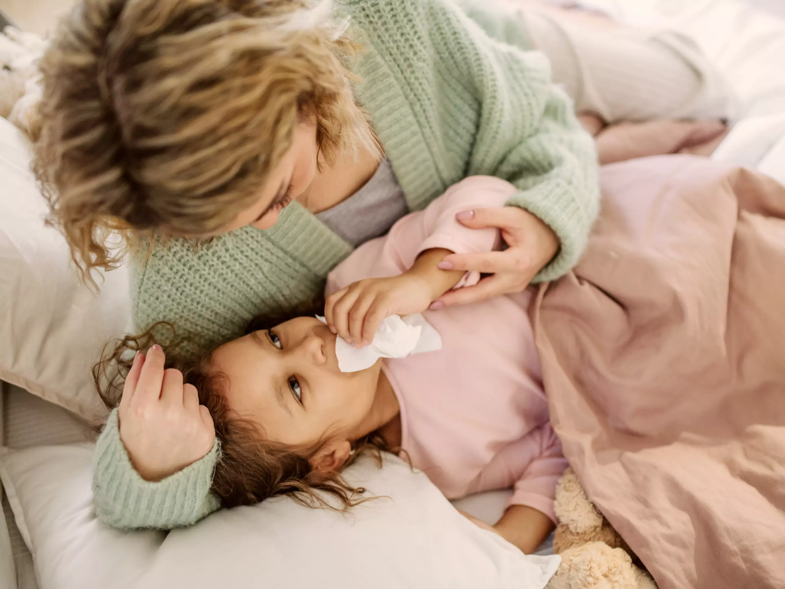Erkältetes Kind mit Mama im Bett
