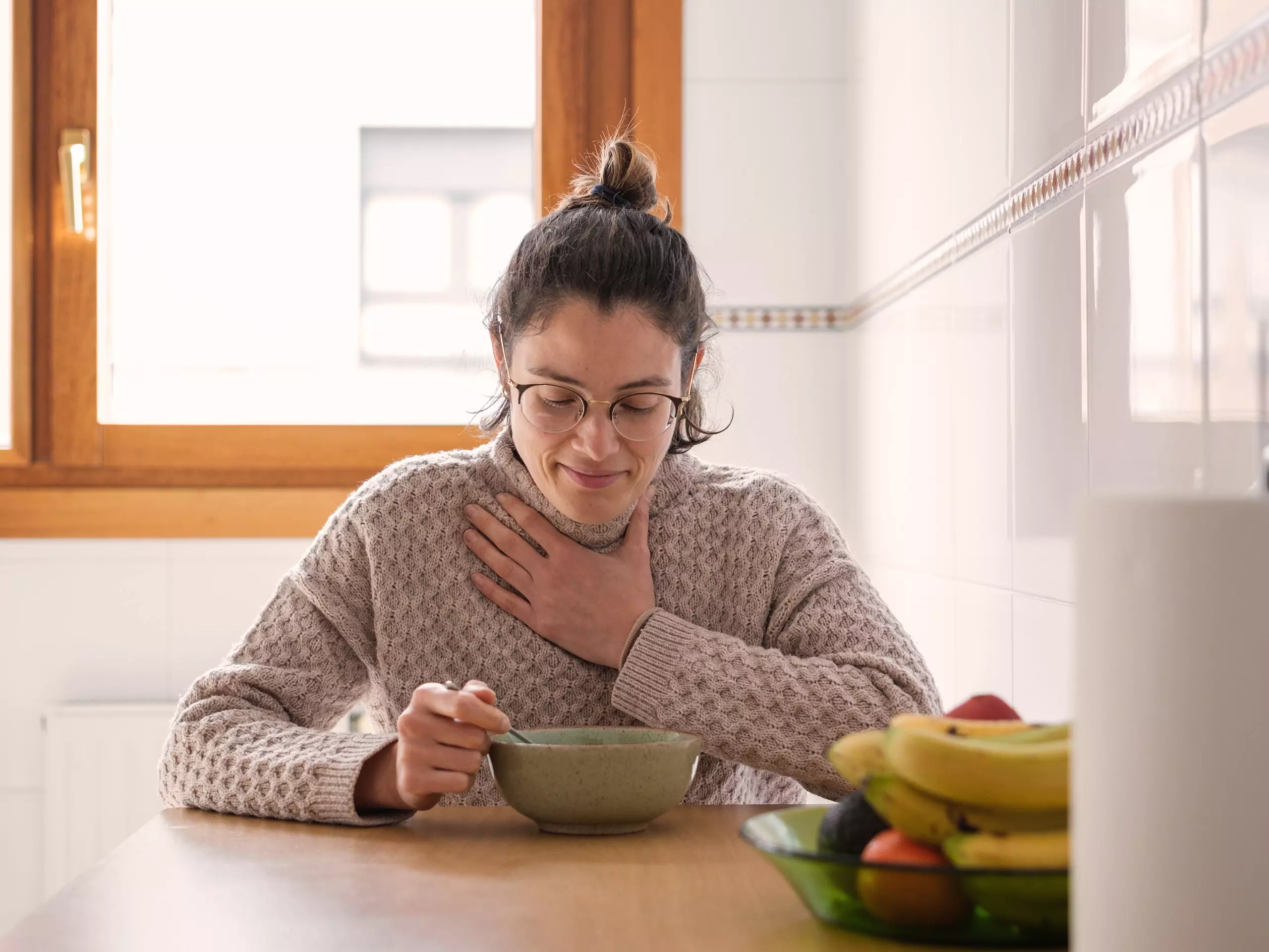 Frau mit Halsschmerzen isst eine Suppe