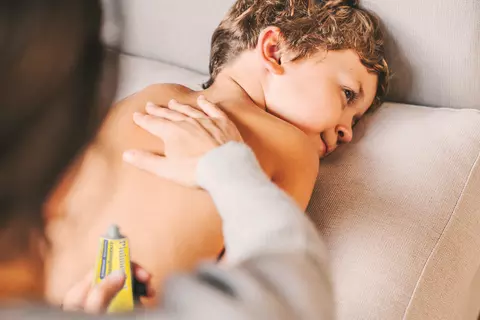 Mutter reibt ihr Kind ein