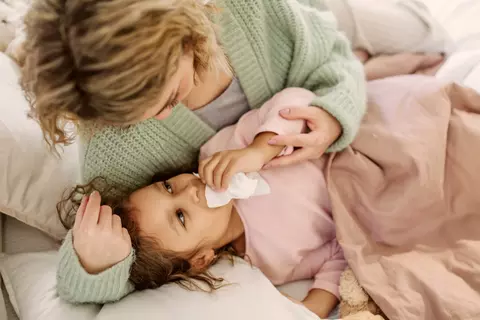 Erkältetes Kind mit Mama im Bett