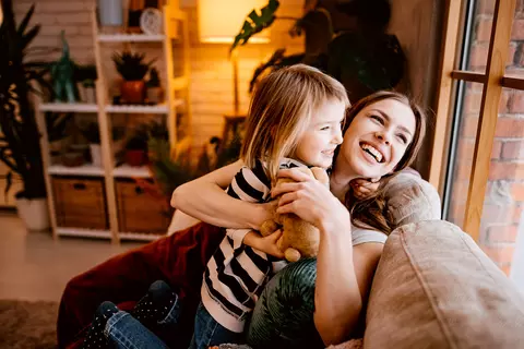 Mutter spielt mit ihrem Kind auf dem Sofa. Kinder sollen bei einer Erkältung nicht inhalieren.