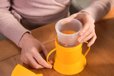 Person zeigt, wie der Innenbecher in den Halter des Inhalators eingesetzt wird