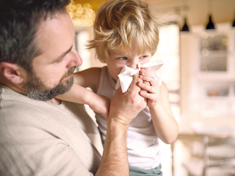 Vater hilft seinem Sohn beim Nase putzen
