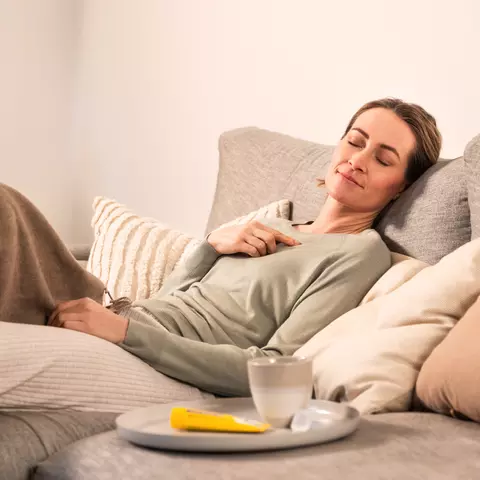 Frau liegt auf der Couch und schläft
